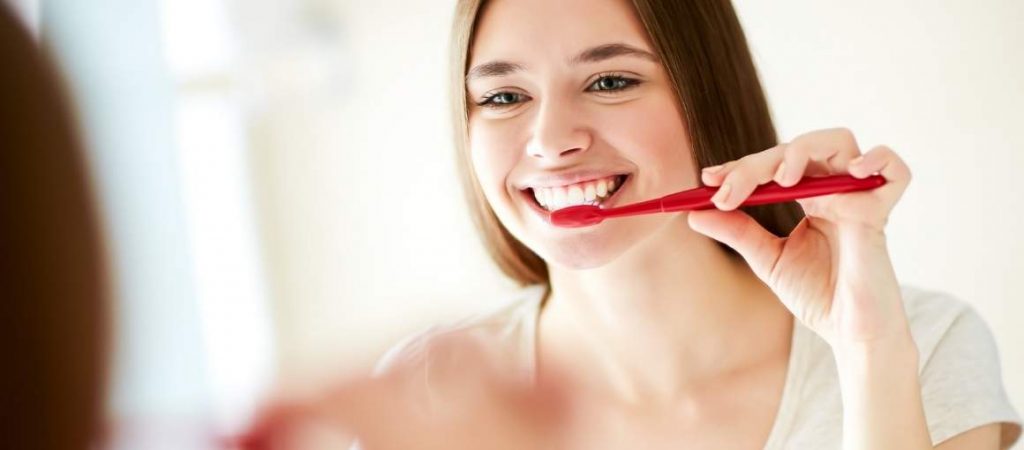 Frau putzt sich lächelnd die Zähne
